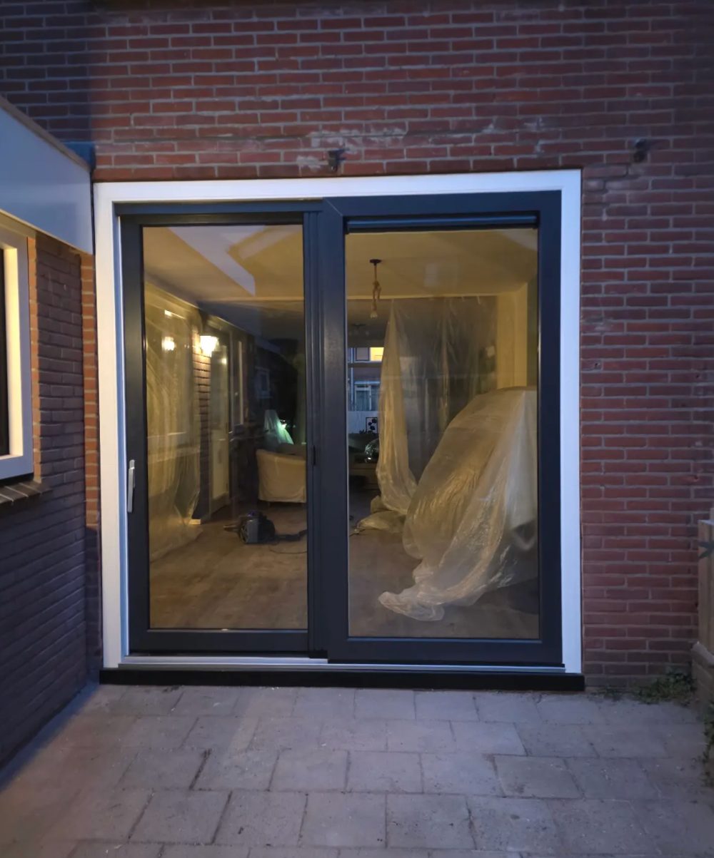 Nieuwe schuifpui in de achtergevel, 's avonds van buiten gezien